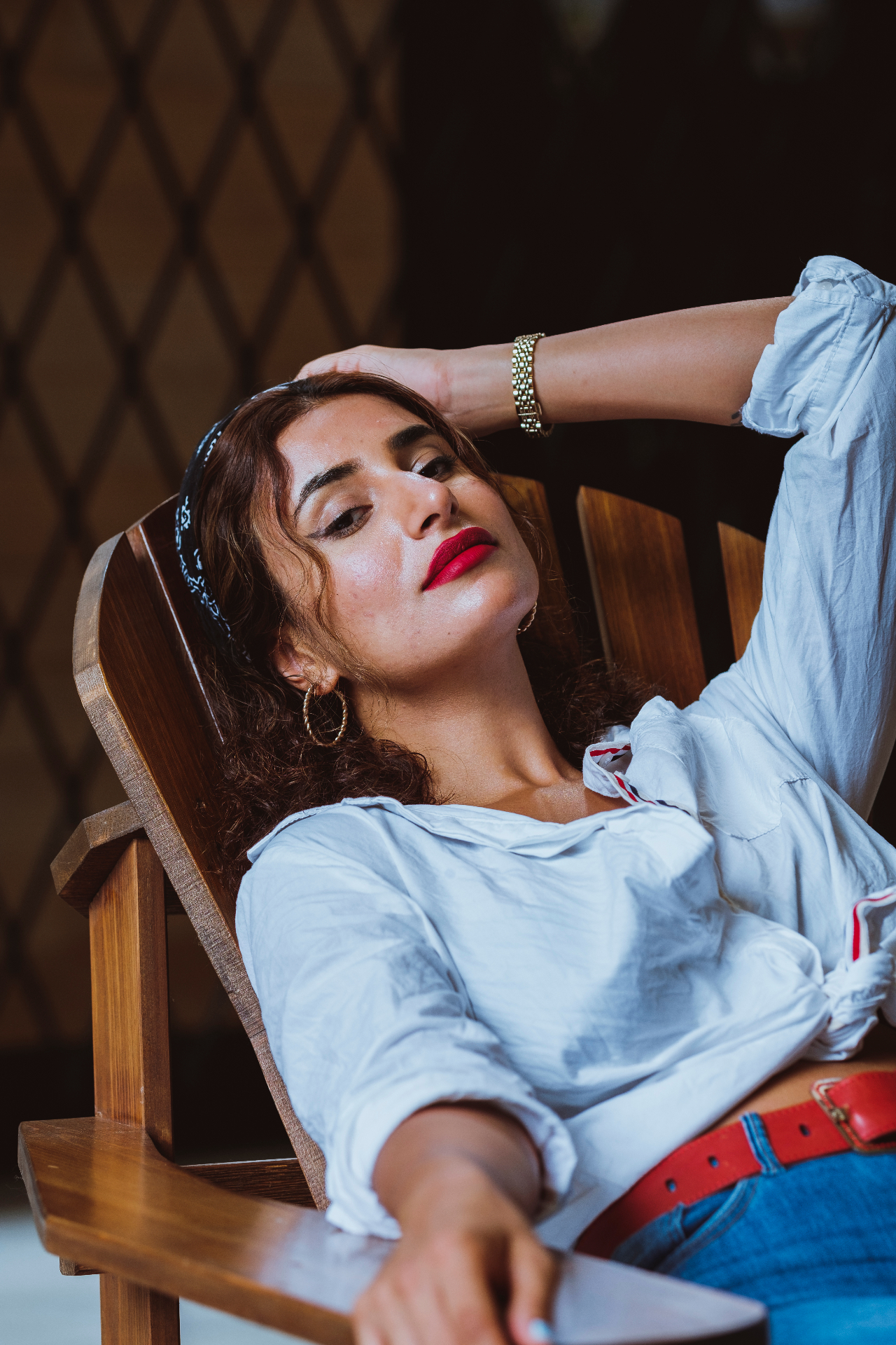 Editorial portrait in a wooden chair with red lip and bandana