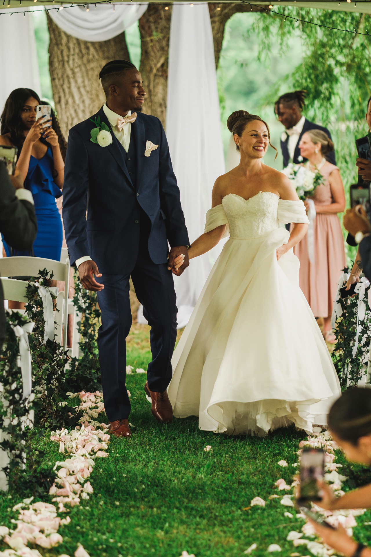 Bride and groom walking the petal-strewn aisle after the ceremony
